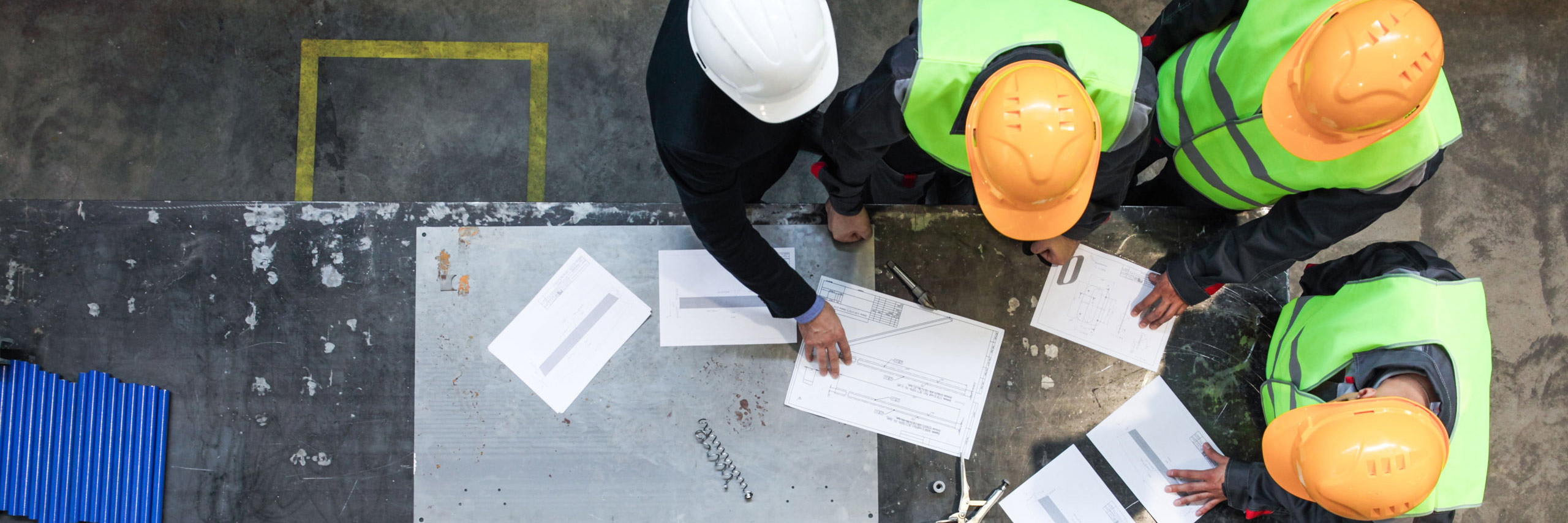 People in hard hats examining printed plans